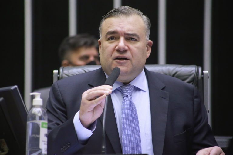 Deputado Ney Leprevost fala ao microfone. Ele é branco, tem o cabelo grisalho e usa um terno azul-marinho