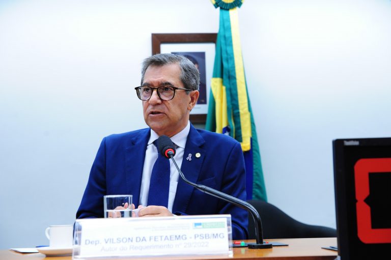 Deputado Vilson da Fetaemg fala ao microfone. Ele é branco, tem cabelo grisalho, usa terno azul escuro e óculos
