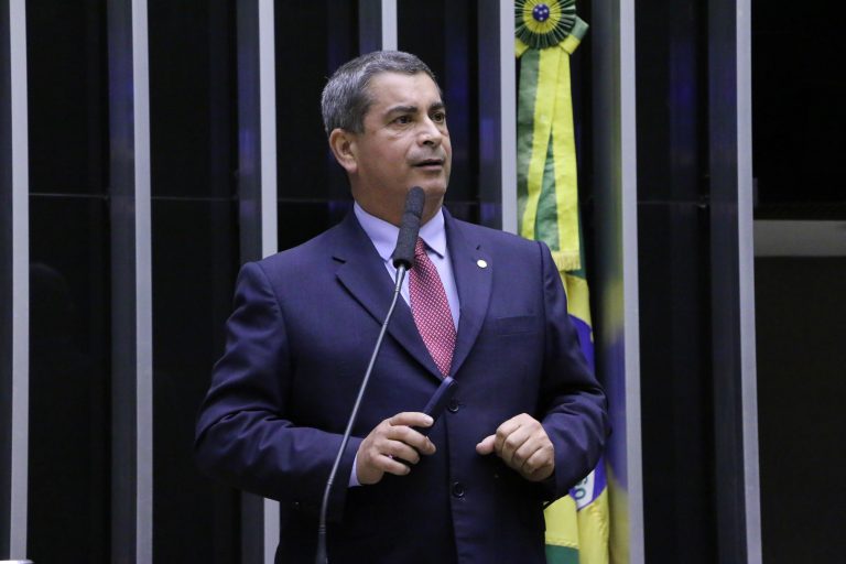 Deputado Coronel Tadeu discursa no Plenário da Câmara. Ele é branco, grisalho, usa terno azul escuro e atrás dele tem uma bandeira do Brasil