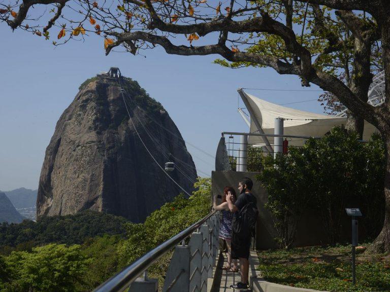 Turistas tiram fotos da vista do alto de um morro
