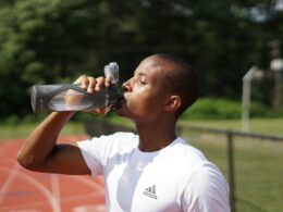 man in white crew neck t-shirt drinking from black sports bottle