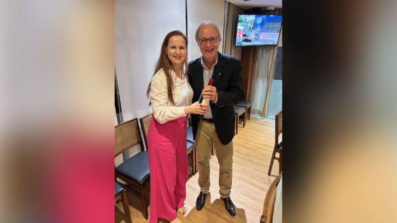 Beatriz Herranz entrega o brinde do aniversariante sorteado, o reitor Anselmo de Abrantes Fortuna / Foto: Divulgação