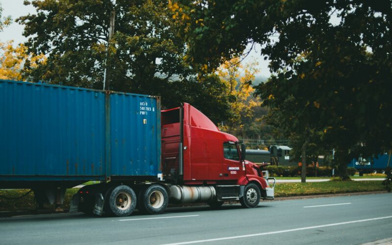 a red semi truck driving down a street