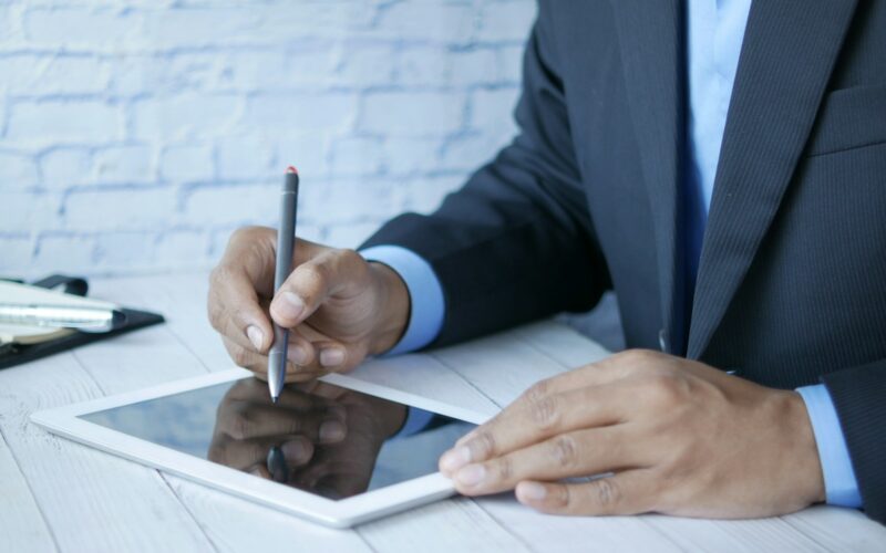 a man in a suit writing on a tablet