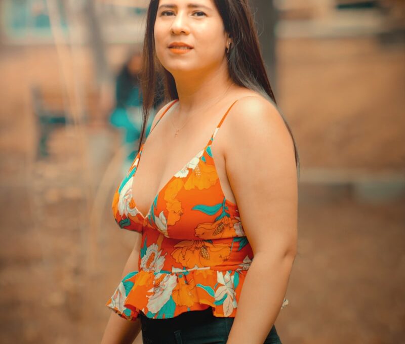 a woman in a floral top poses for a picture