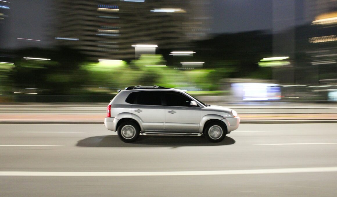 a white suv driving down a city street at night