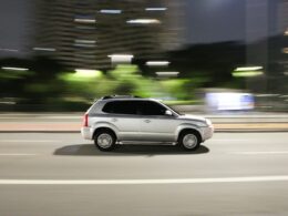 a white suv driving down a city street at night