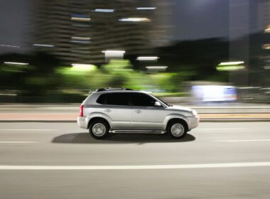 a white suv driving down a city street at night