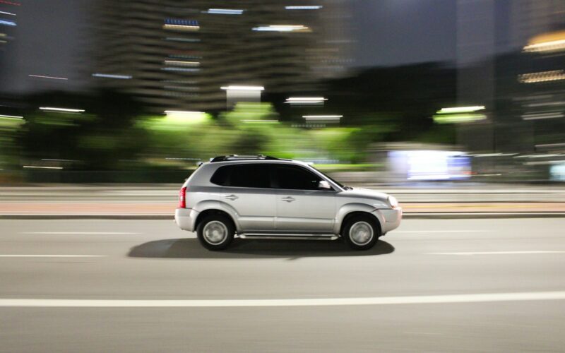 a white suv driving down a city street at night