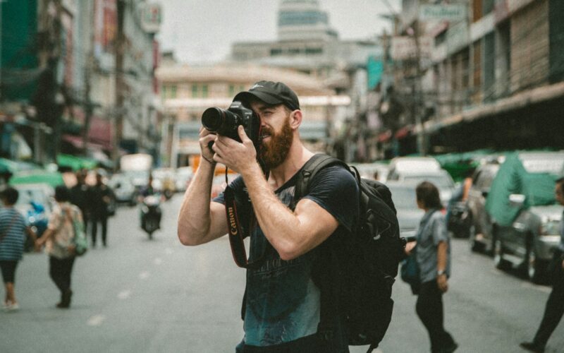 shallow focus photography of man using a DSLR camera