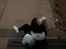 a person sitting on a bench on a sidewalk