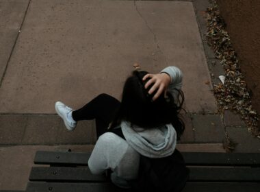 a person sitting on a bench on a sidewalk