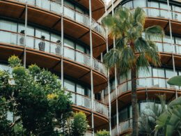 a tall building with balconies and palm trees in front of it