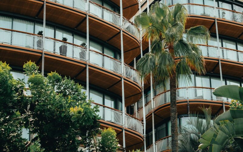 a tall building with balconies and palm trees in front of it
