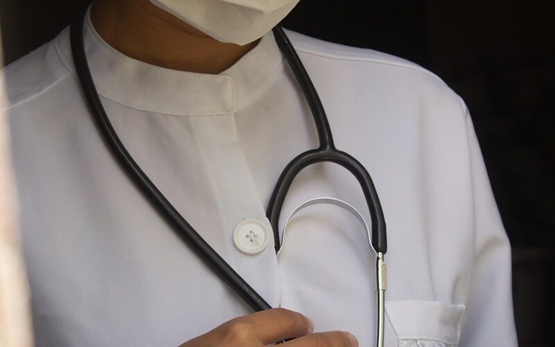 a woman wearing a medical mask and holding a stethoscope