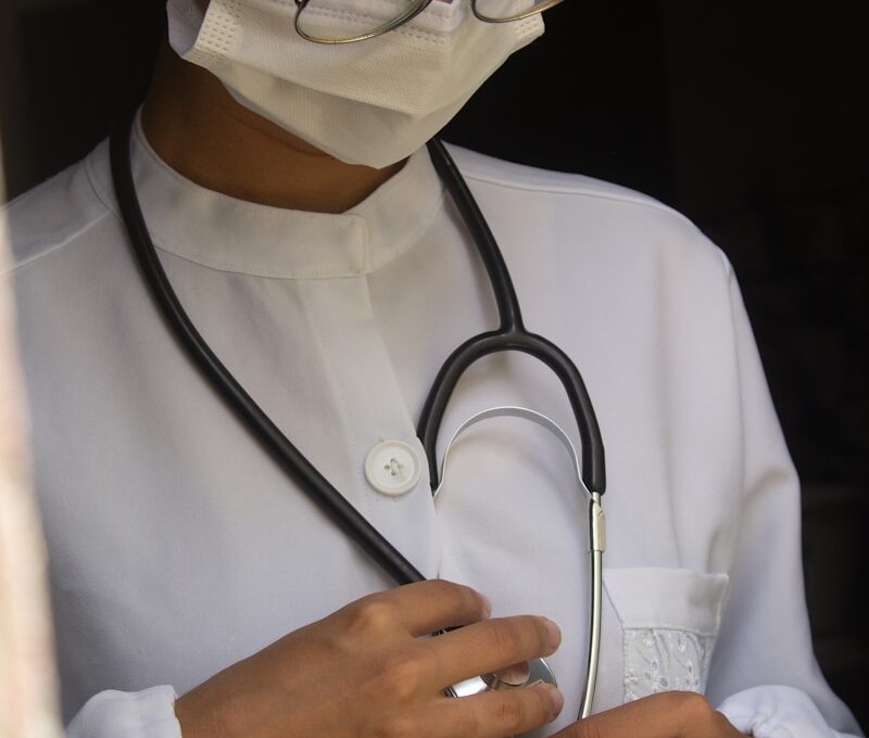 a woman wearing a medical mask and holding a stethoscope