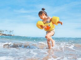 girl playing beside body of water during daytime
