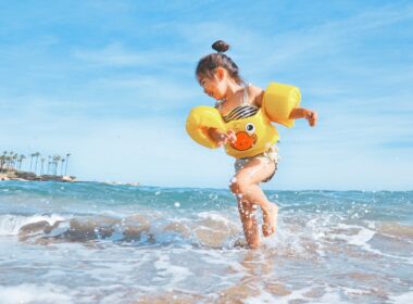 girl playing beside body of water during daytime