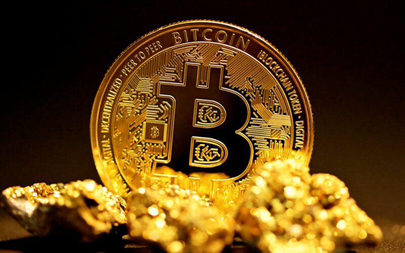 a bitcoin sitting on top of a pile of gold nuggets