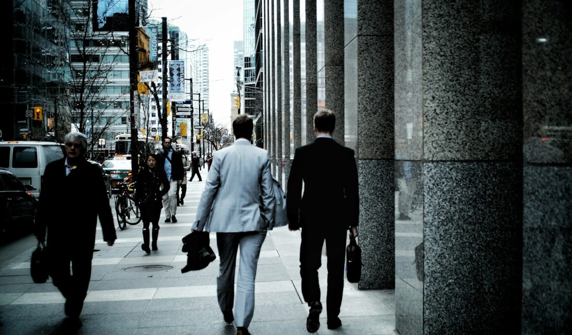 people walking on sidewalk pathway beside road with vehicles and high-rise buildings during daytime