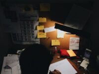 a person sitting at a desk in front of a lamp