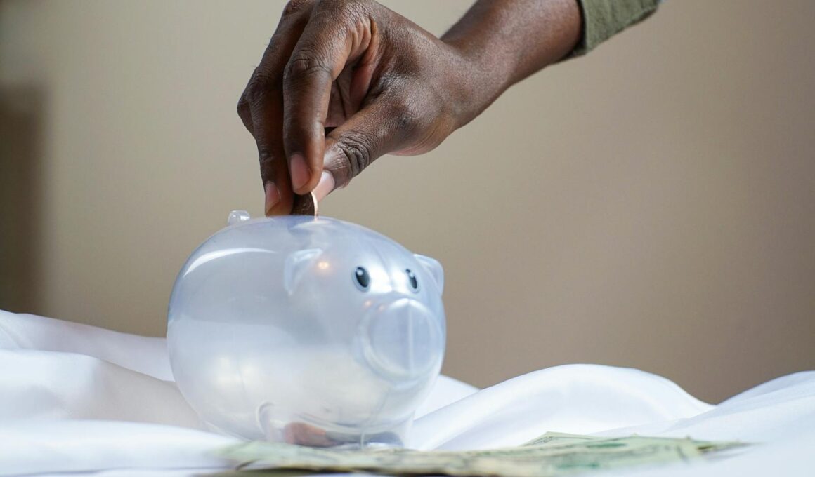 Close-up of a person's hand placing coins into a transparent piggy bank to save money.