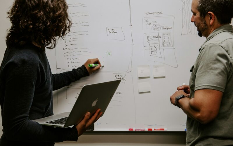 man wearing gray polo shirt beside dry-erase board