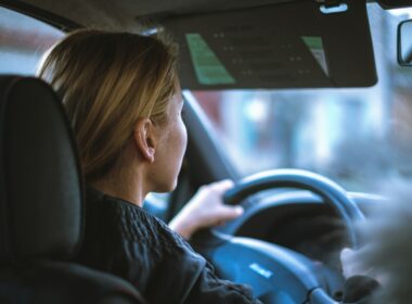a woman sitting in a car with a steering wheel