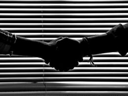 Silhouette of two people shaking hands symbolizing partnership and trust.