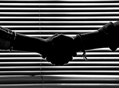 Silhouette of two people shaking hands symbolizing partnership and trust.