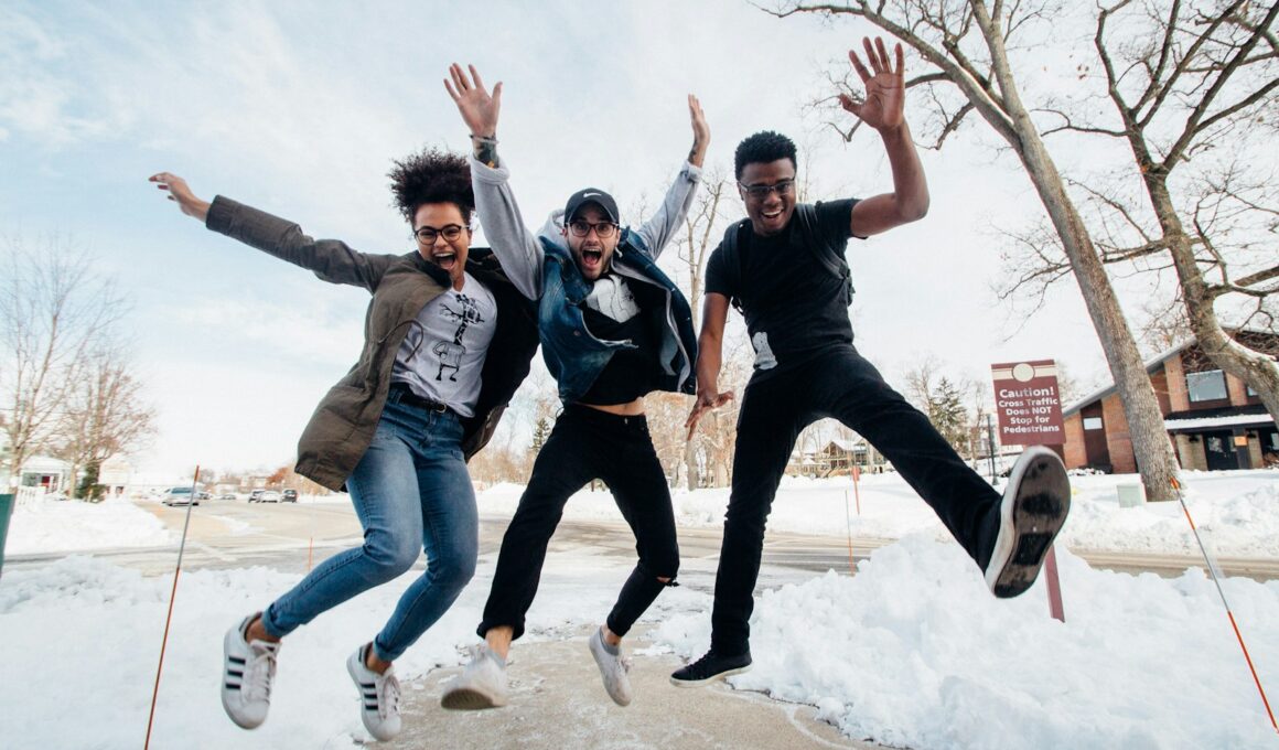 photo of three men jumping on ground near bare trees during daytime