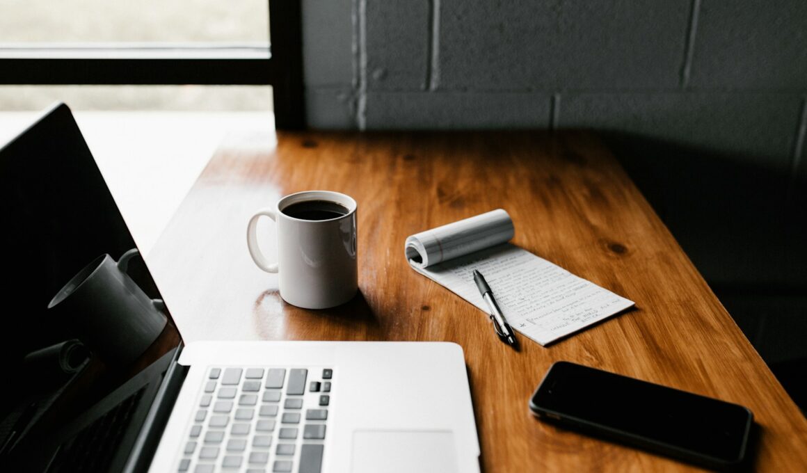 MacBook Pro, white ceramic mug,and black smartphone on table