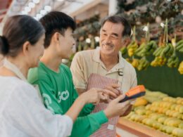 a couple of people standing in front of a fruit stand