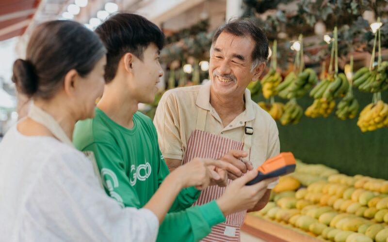 a couple of people standing in front of a fruit stand