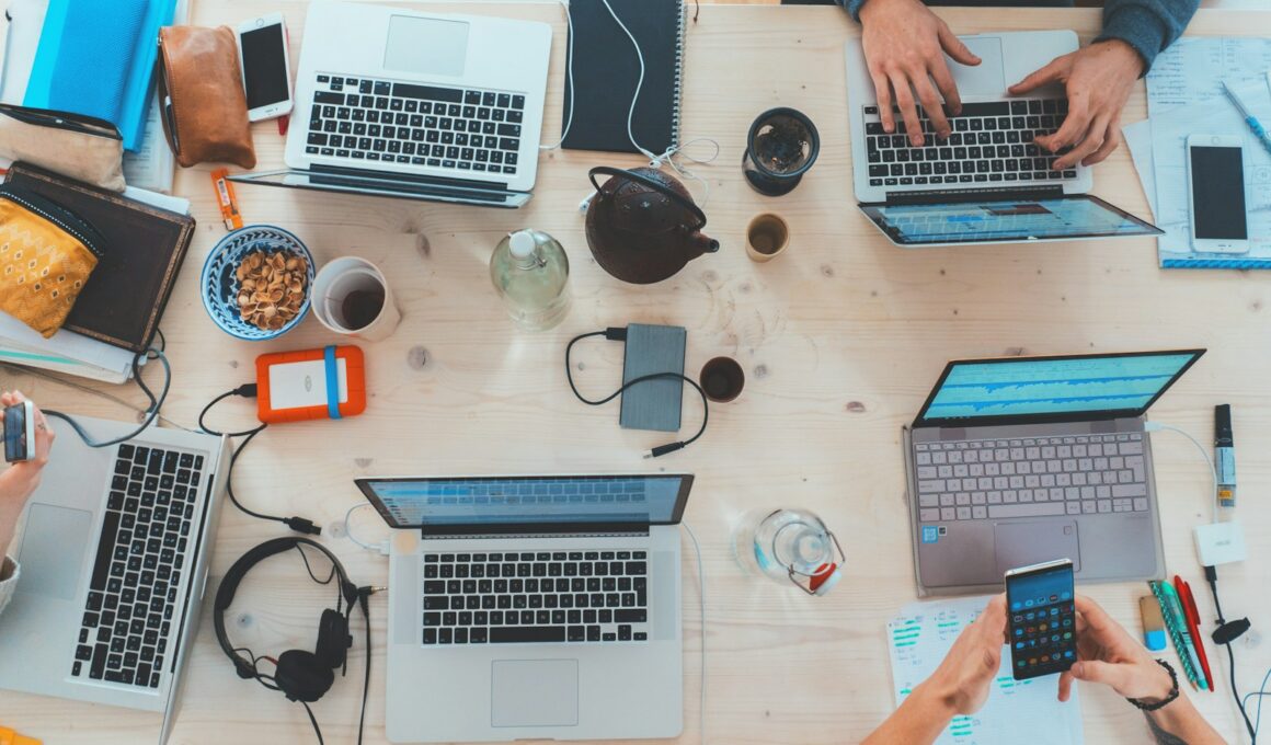 people sitting down near table with assorted laptop computers