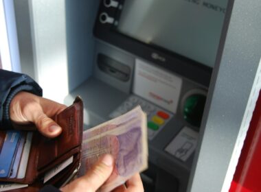person holding brown leather wallet and banknotes