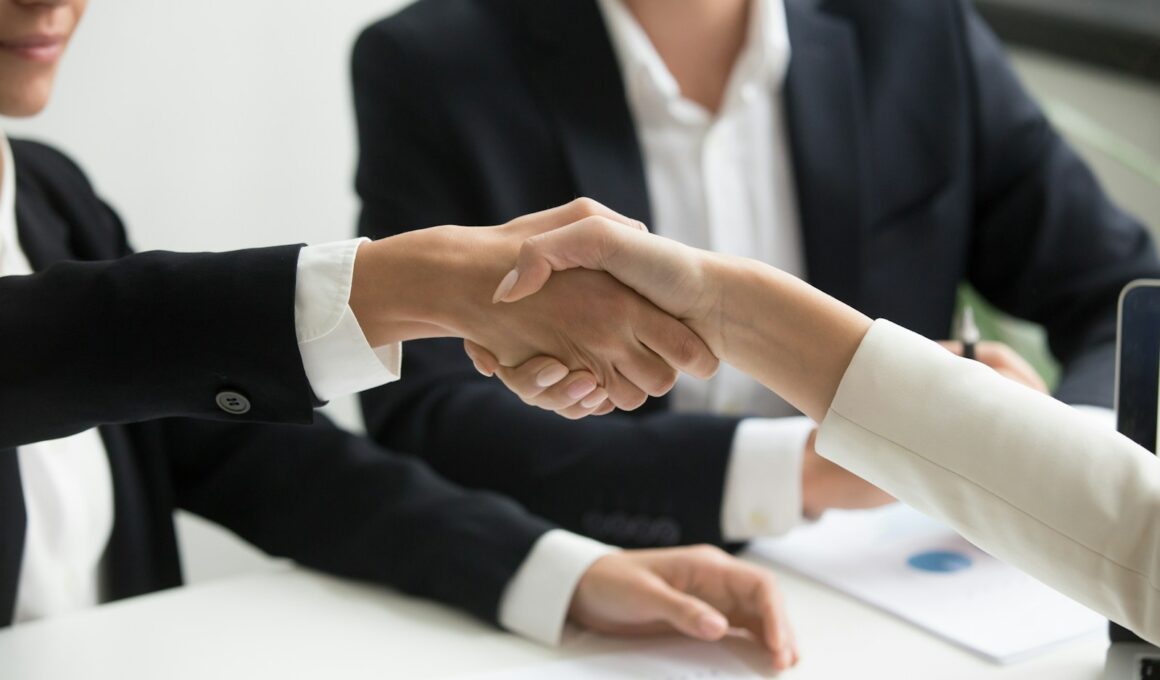 two people shaking hands in front of a laptop