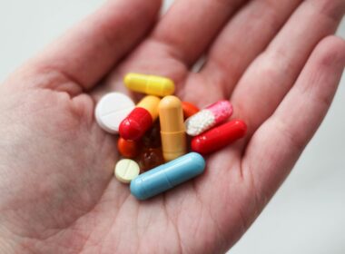 orange and white medication pill on persons hand