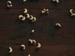 Cashews are scattered on a dark wooden surface.