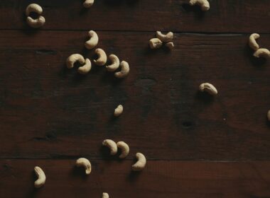 Cashews are scattered on a dark wooden surface.