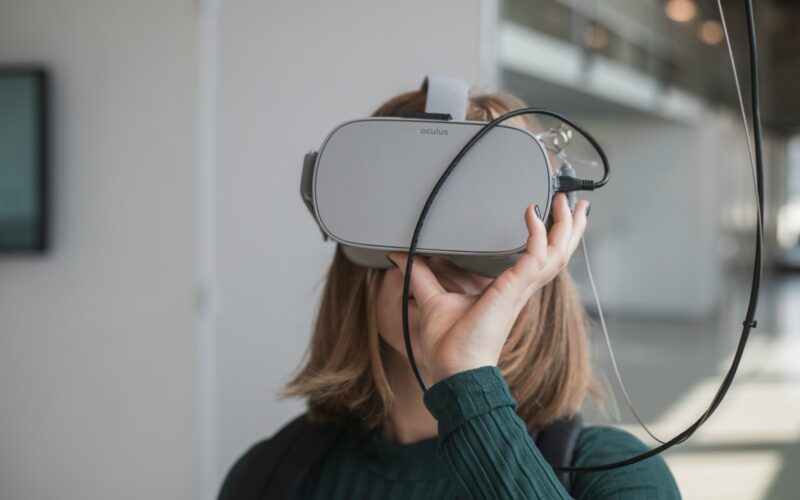 woman in black sweater holding white and black vr goggles