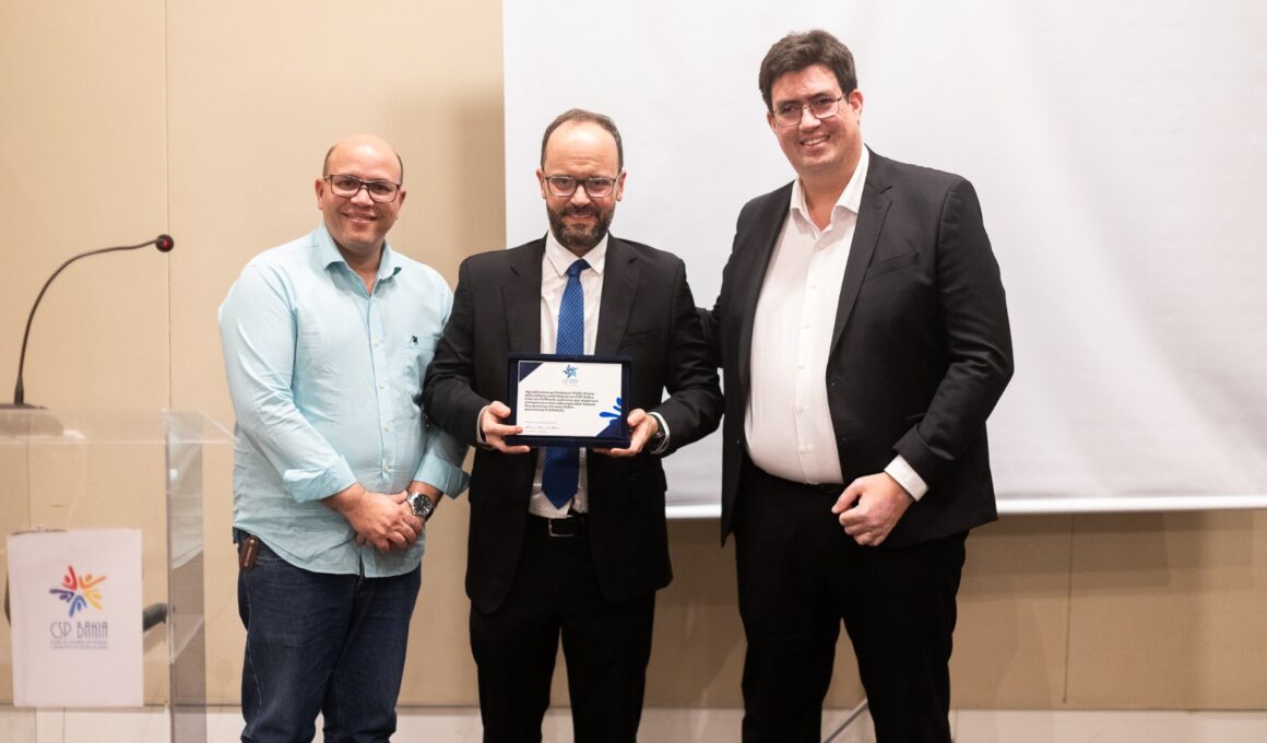 O vice-presidente do CSP Bahia, Ulisses Brito, e o presidente da entidade, Antonio Daniel Mota, entregam placa de homenagem ao palestrante / Foto: Vitor Moreira / Divulgação