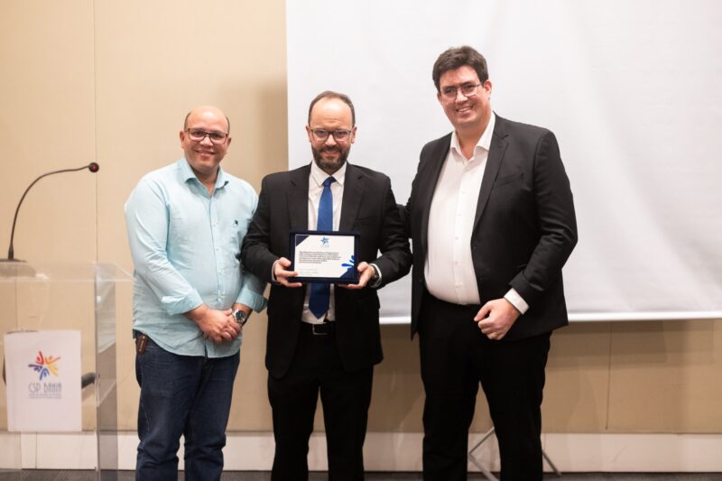 O vice-presidente do CSP Bahia, Ulisses Brito, e o presidente da entidade, Antonio Daniel Mota, entregam placa de homenagem ao palestrante / Foto: Vitor Moreira / Divulgação