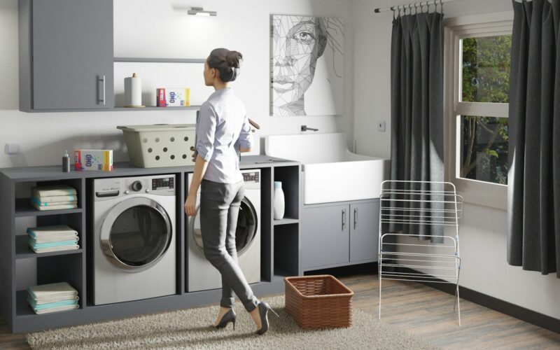 a woman standing in a laundry room next to a washer and dryer