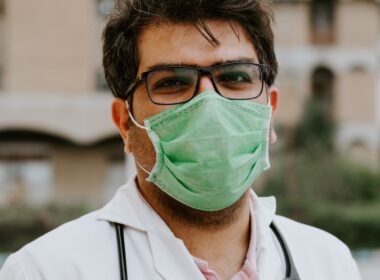man in white scrub suit wearing green mask