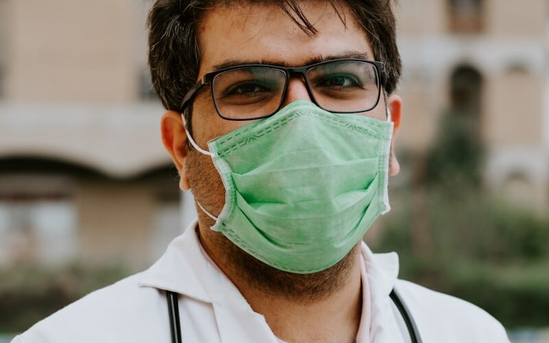 man in white scrub suit wearing green mask