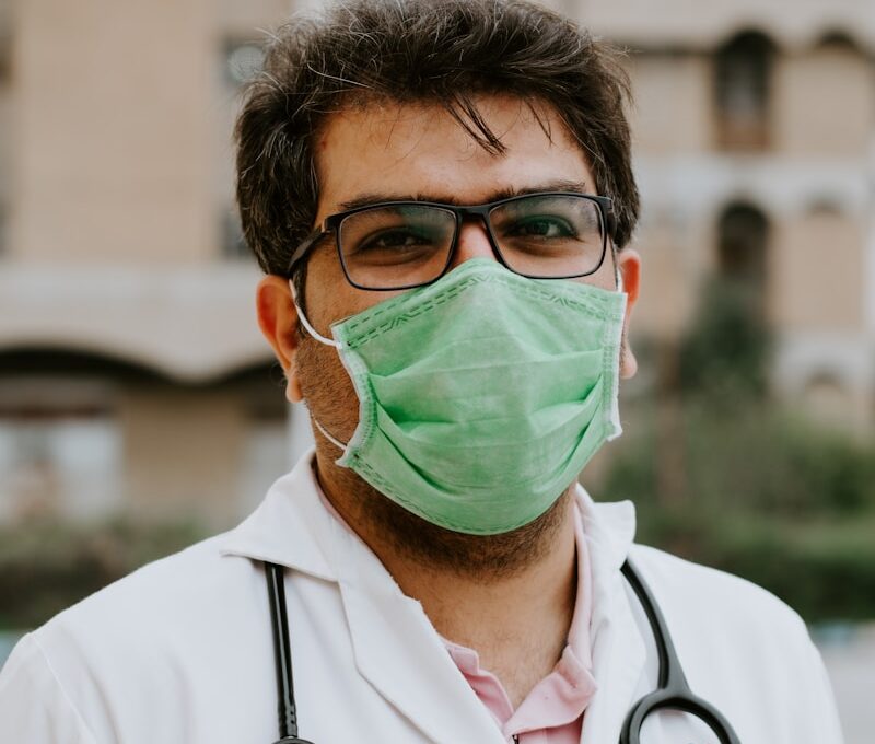 man in white scrub suit wearing green mask