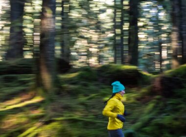 a person running in the woods with trees in the background