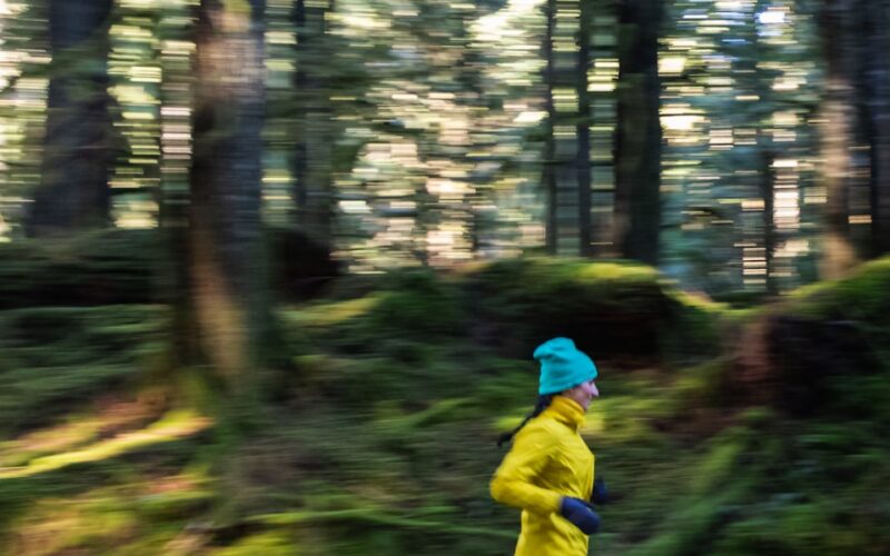 a person running in the woods with trees in the background