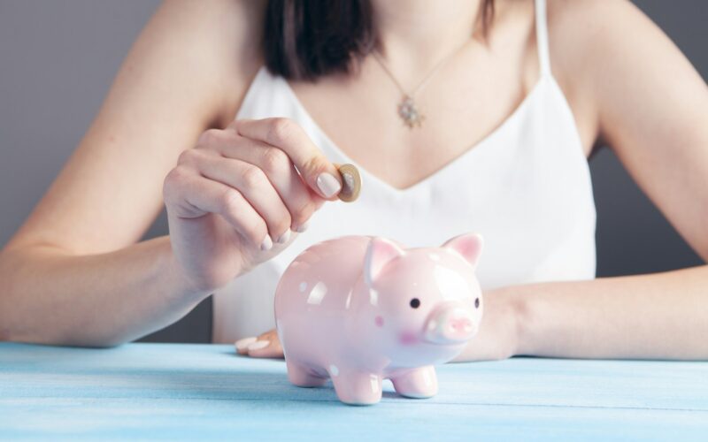 woman in white tank top holding pink pig figurine